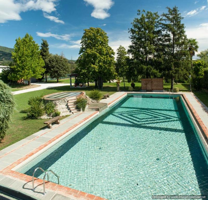 una piscina a sfioro in un cortile con alberi e erba di BASILIMO di Home Hill a Capannori
