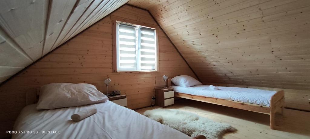 twee bedden in een houten kamer met een raam bij Chata DUDZIAKÓWKA in Werlas