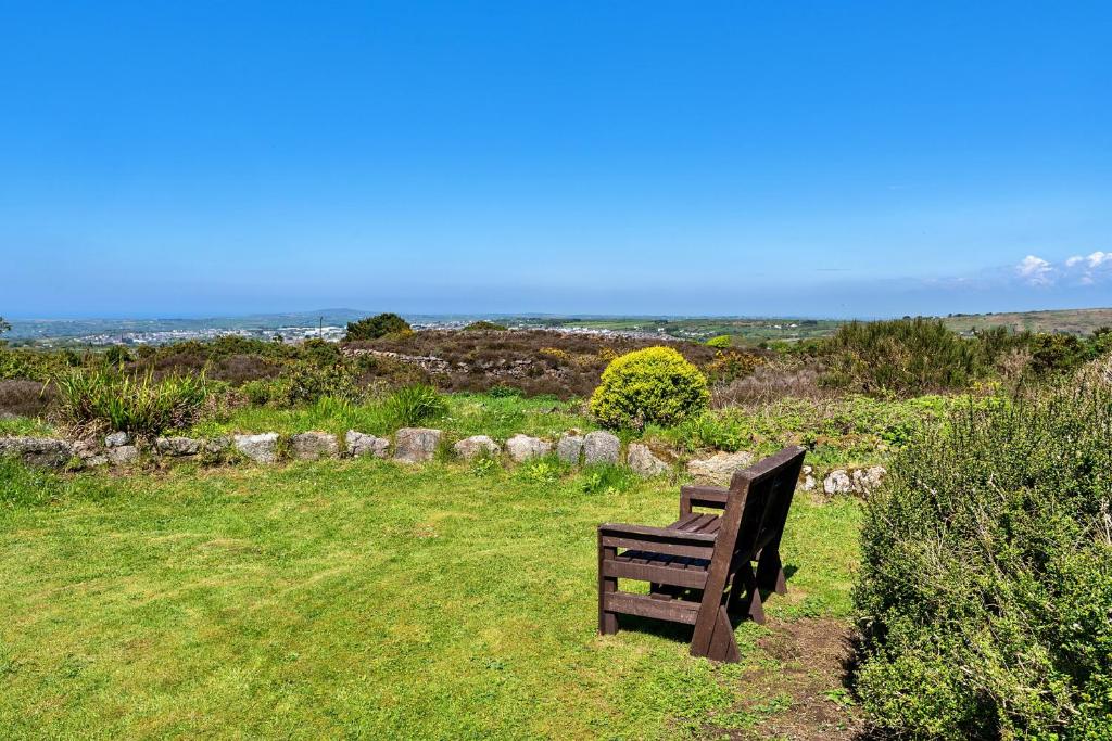 a wooden bench sitting on top of a grass field at Finest Retreats - Trethew Cottage in Carnbrea