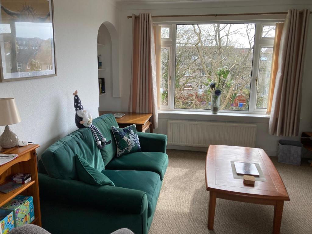 ein Wohnzimmer mit einem grünen Sofa und einem Tisch in der Unterkunft The Waterside Apartment 6 in Largs
