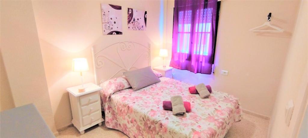 a small bedroom with a bed with pink sheets at Apartamento Tres Carabelas II, AC, Wifi, Parking in Sanlúcar de Barrameda