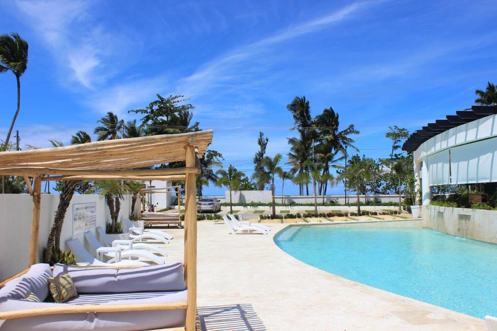 a pool with lounge chairs next to a building at Amar'e Aparthotel & Spa in Las Terrenas