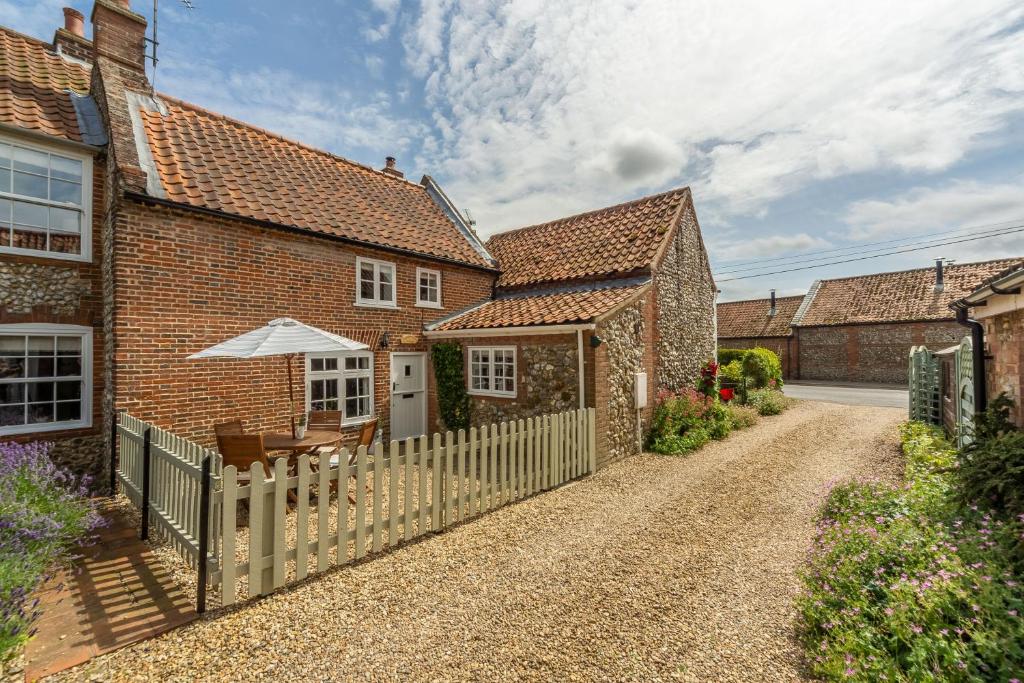 a house with a fence and a table and an umbrella at Sextons Yard Cottage in Docking