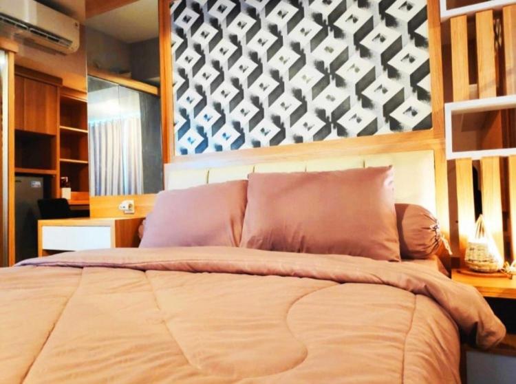 ein Schlafzimmer mit einem großen Bett mit einer Wand in der Unterkunft Apartemen grand kamala lagoon in Kayuringin
