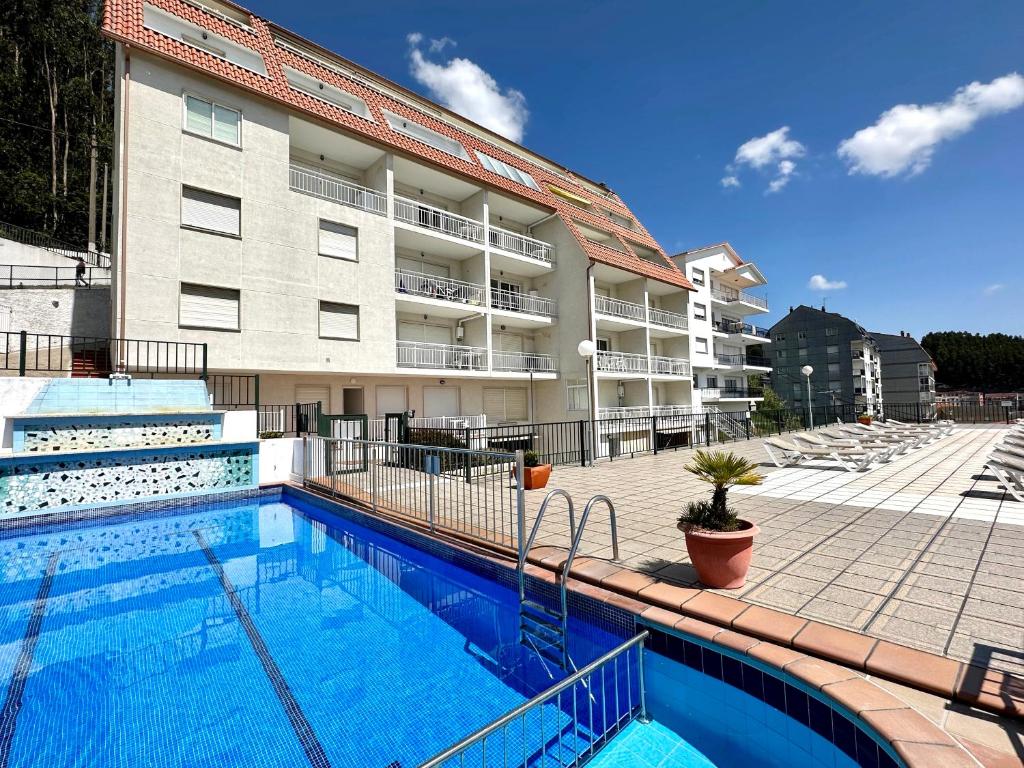 um hotel com piscina em frente a um edifício em Apartamentos Park Raxo em Raxó