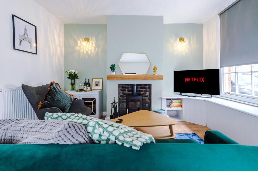 a living room with a green couch and a tv at Pyecroft Cottage in Chester