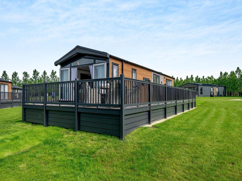 a house with a large deck on the grass at Pheasant Lodge in Nawton