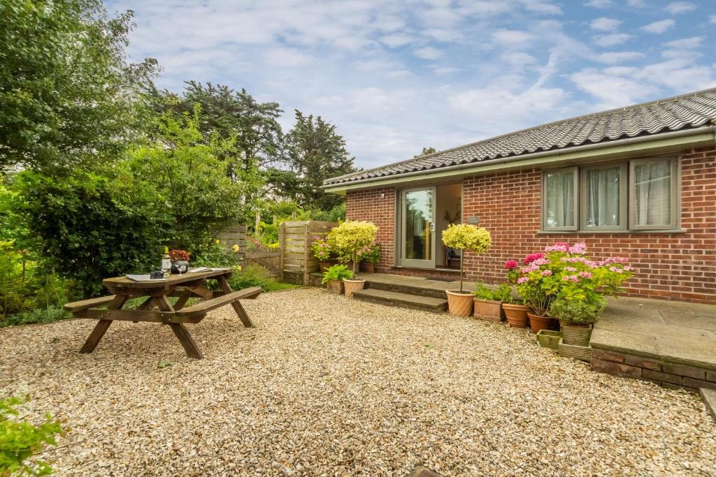 un patio trasero con una mesa de picnic y una casa de ladrillo en Stiffkey Hideaway, en Stiffkey