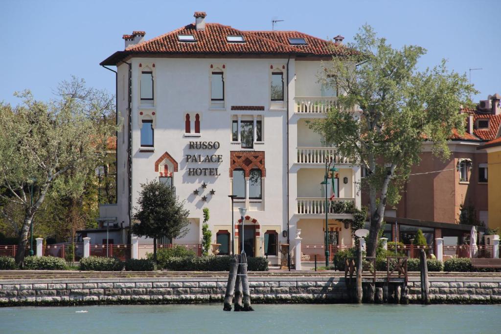un gran edificio blanco junto al agua en Hotel Russo Palace, en Lido de Venecia