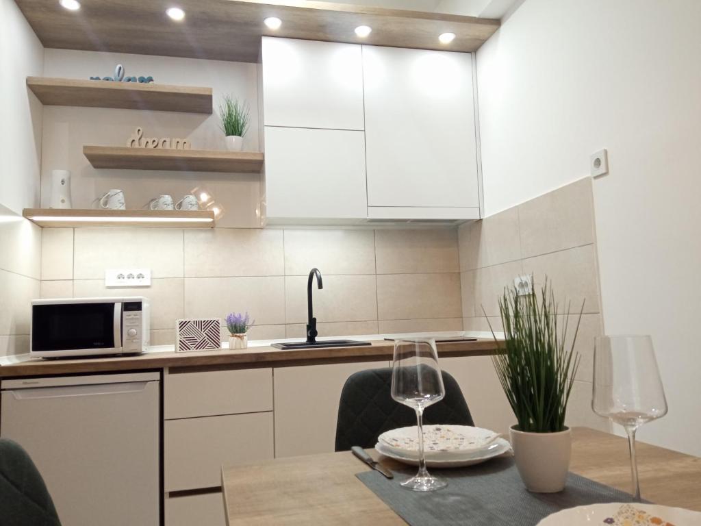 una cocina con armarios blancos y una mesa con sillas. en Apartman Zara en Jagodina