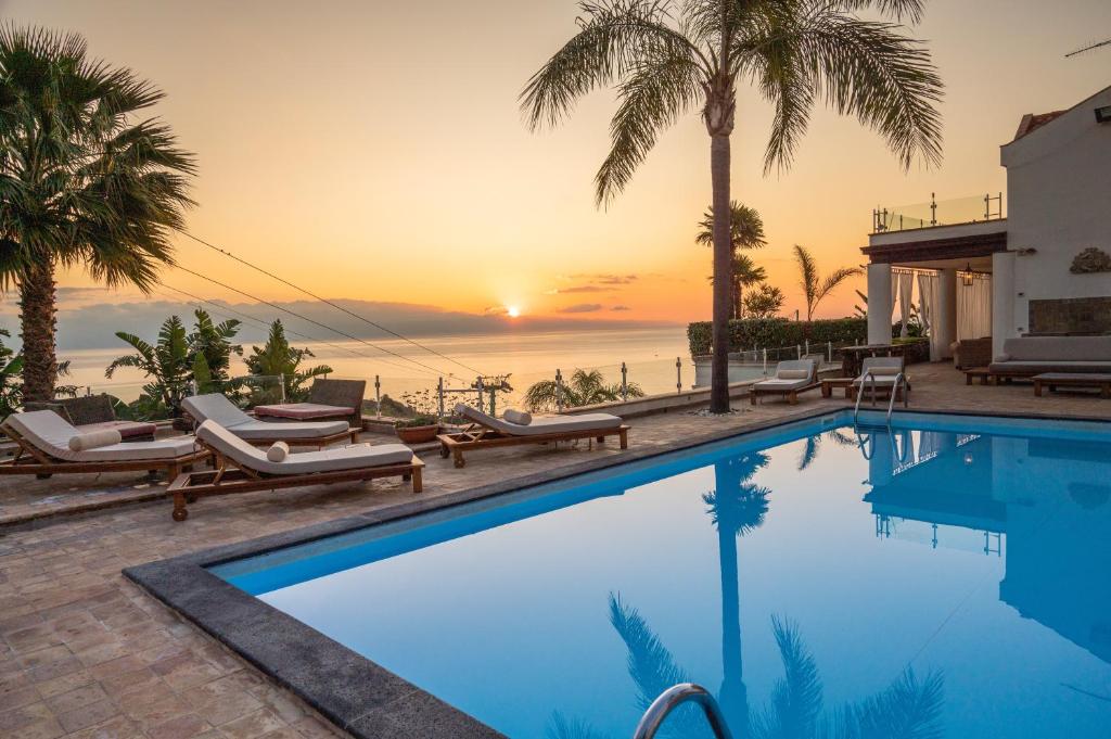 una piscina con vistas al océano al atardecer en Villa Zagara Garden Spectacular Sea View in Taormina, en Taormina