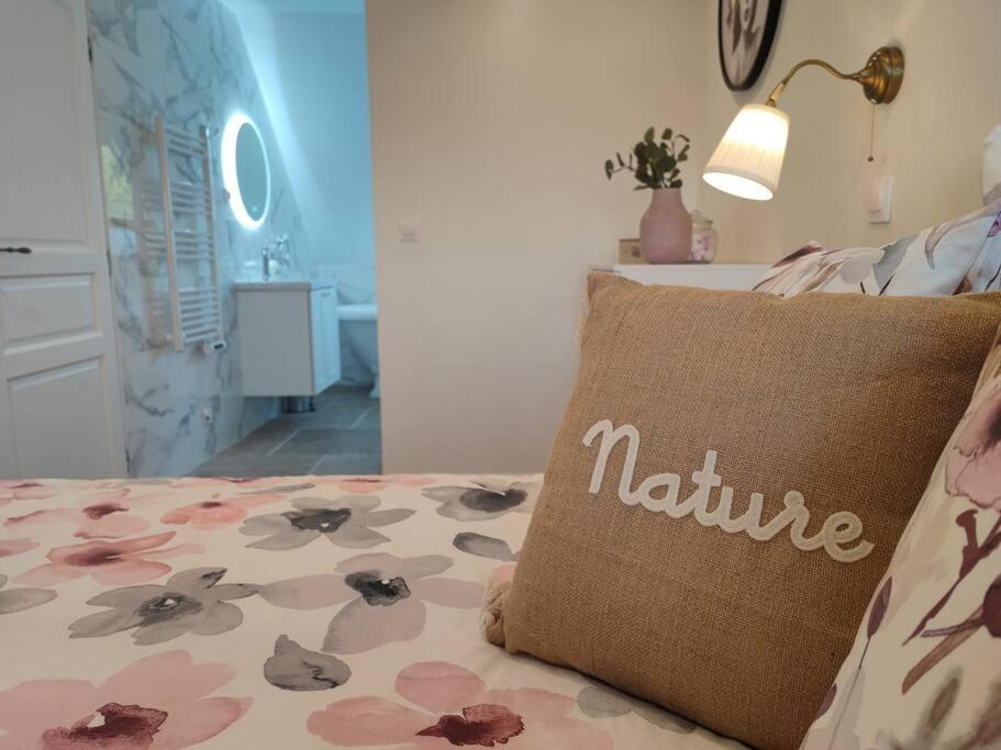 a pillow with the word nature sitting on a bed at La Suite in Vron