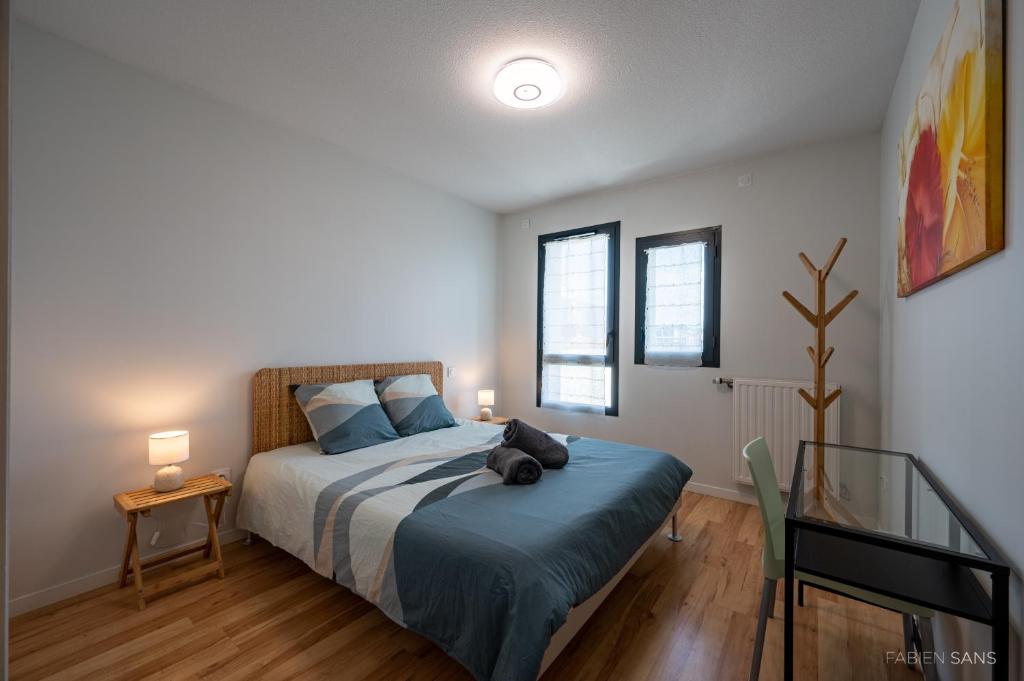 1 dormitorio con 1 cama con manta azul y 2 ventanas en Le Saint Exupéry - T3 Centre Ville Avec Balcon + Parking Gratuit en Toulouse