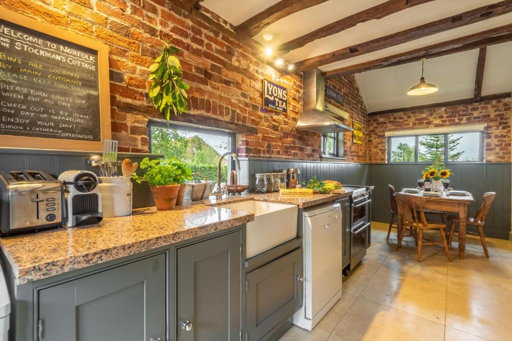 a kitchen with a brick wall and a counter top at Stockmans Cottage in Foulsham