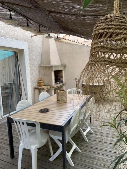 a wooden table and white chairs on a patio at small house 6p in bormes, quiet , hill-view in Bormes-les-Mimosas