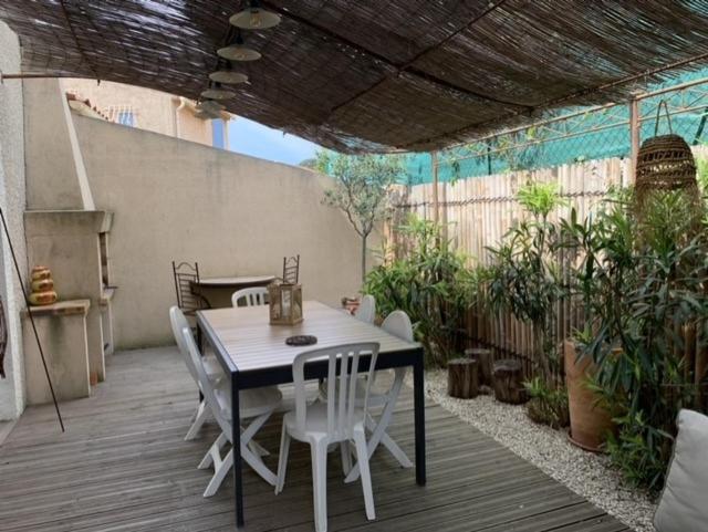 a patio with a table and chairs on a deck at small house 6p in bormes, quiet , hill-view in Bormes-les-Mimosas