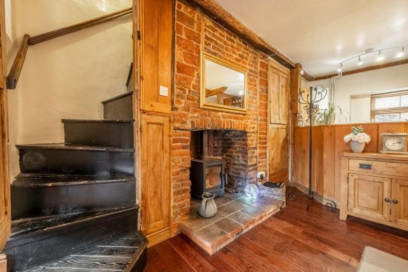 a brick fireplace in a living room with a brick wall at Harbour View Cottage in Wells next the Sea