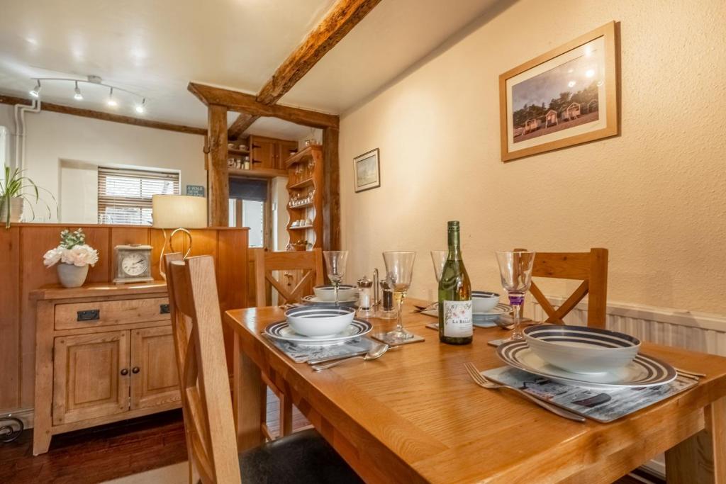 a dining room with a wooden table with plates and glasses at Harbour View Cottage in Wells next the Sea