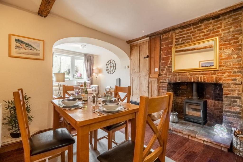 a dining room with a table and a fireplace at Harbour View Cottage in Wells next the Sea