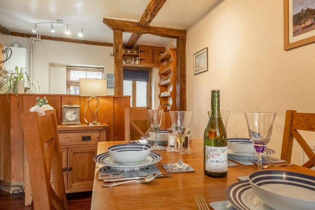 a dining room table with a bottle of wine on it at Harbour View Cottage in Wells next the Sea