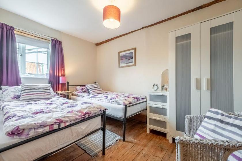 a bedroom with two beds and a window at Harbour View Cottage in Wells next the Sea
