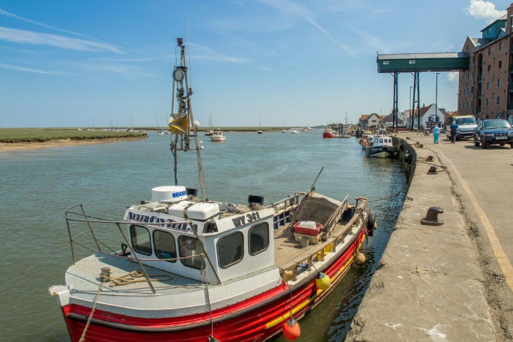 a boat is docked at a dock in the water at Harbour View Cottage in Wells next the Sea