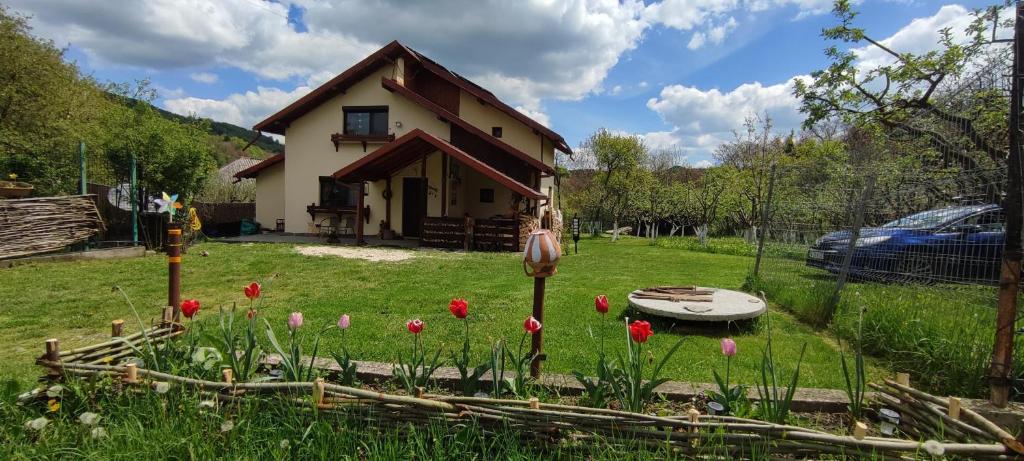 a house with a bunch of flowers in the yard at Cottage in traditional village Bradulet, Arges county in Brăduleţ