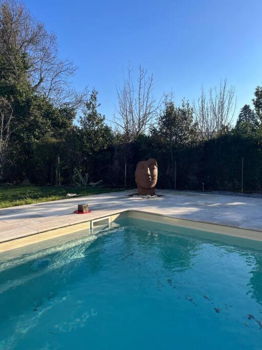une grande piscine avec une sculpture dans une cour dans l'établissement Location Appartement saisonnier, à Clermont-lʼHérault