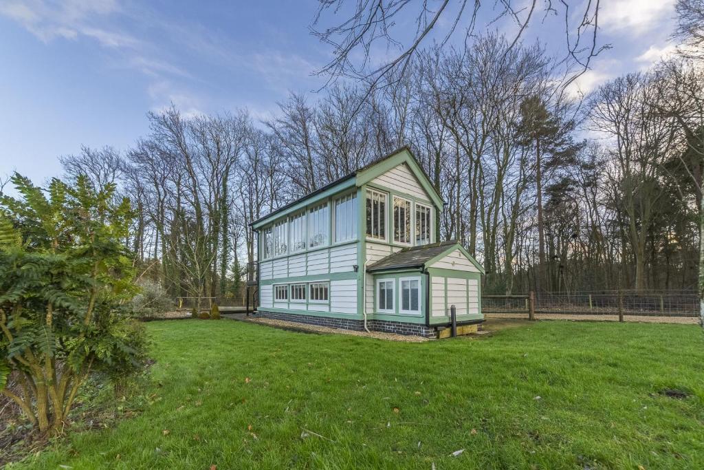 a green and white house on a grass field at The Signal Box in Melton Constable