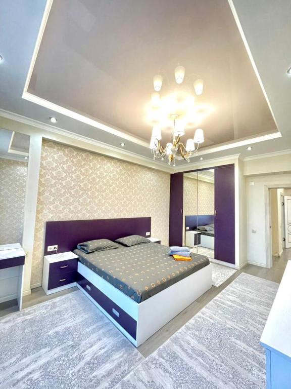 Habitación grande con cama grande y lámpara de araña. en Elite apartment in street Moskovskay 191, en Bishkek