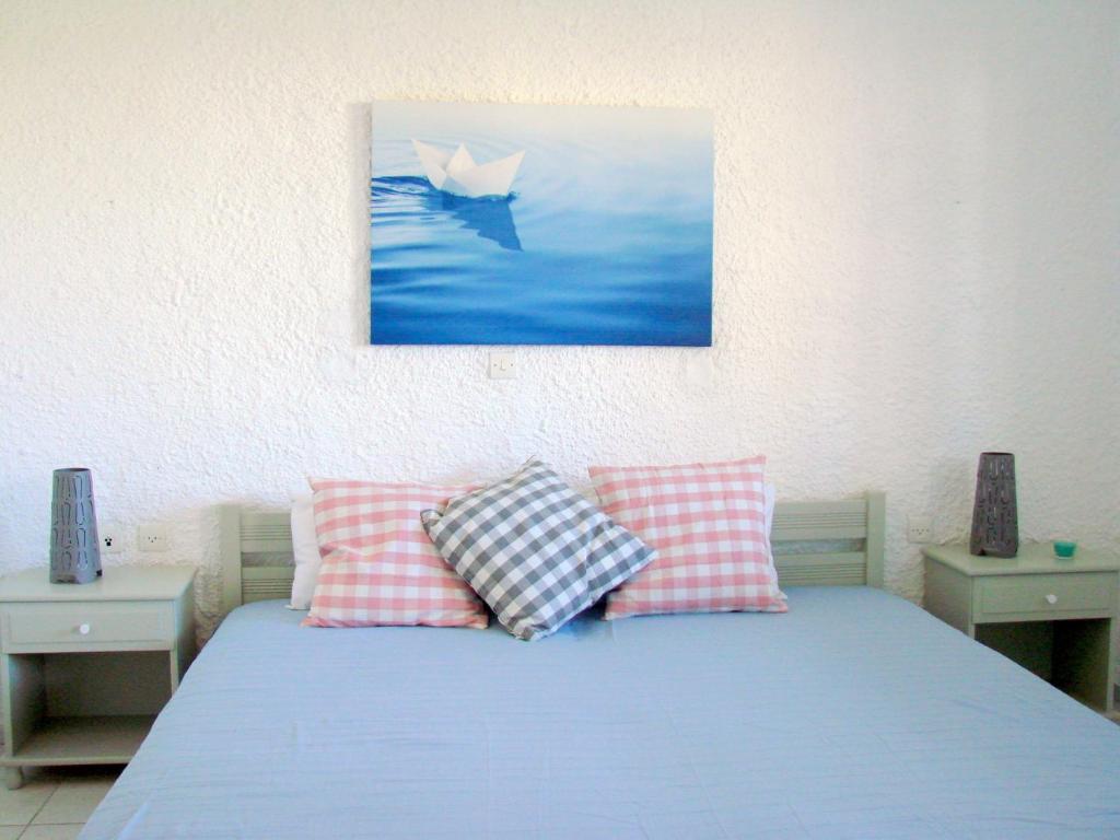 uma cama com duas almofadas e uma foto de um barco em Aegialis Studios & Rooms em Galissas