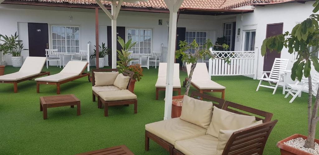 a patio with chairs and tables on a green lawn at Villa las Flores in Adeje