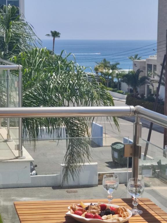 uma mesa com um prato de comida e copos de vinho numa varanda em Dess Dream Vacation 1 bedroom Flat steps from Da Costa Bay, Protaras em Protaras