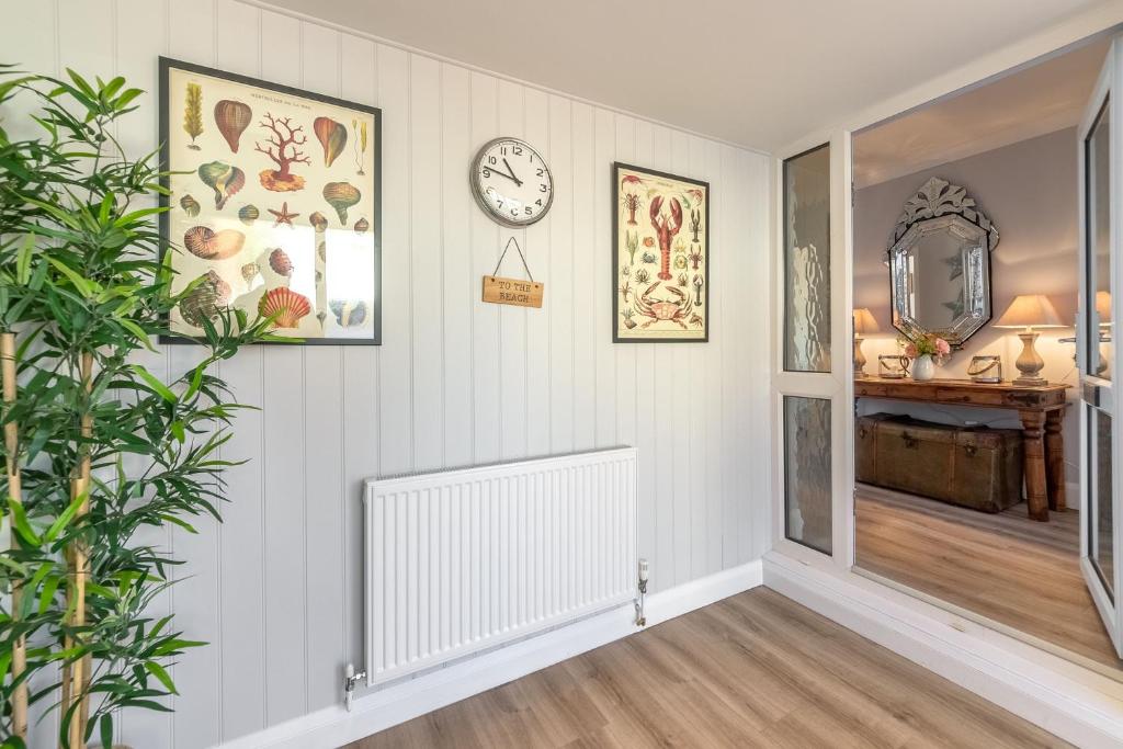 a hallway with white walls and a clock on the wall at Kipling House 8 in Wells next the Sea