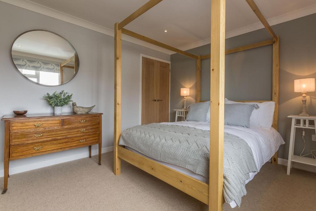 a bedroom with a four poster bed and a mirror at Kipling House 8 in Wells next the Sea