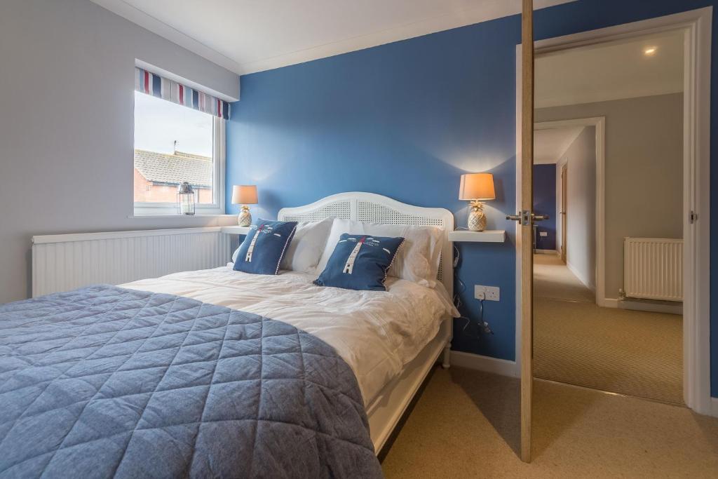a blue bedroom with a large bed with blue walls at Kipling House 8 in Wells next the Sea