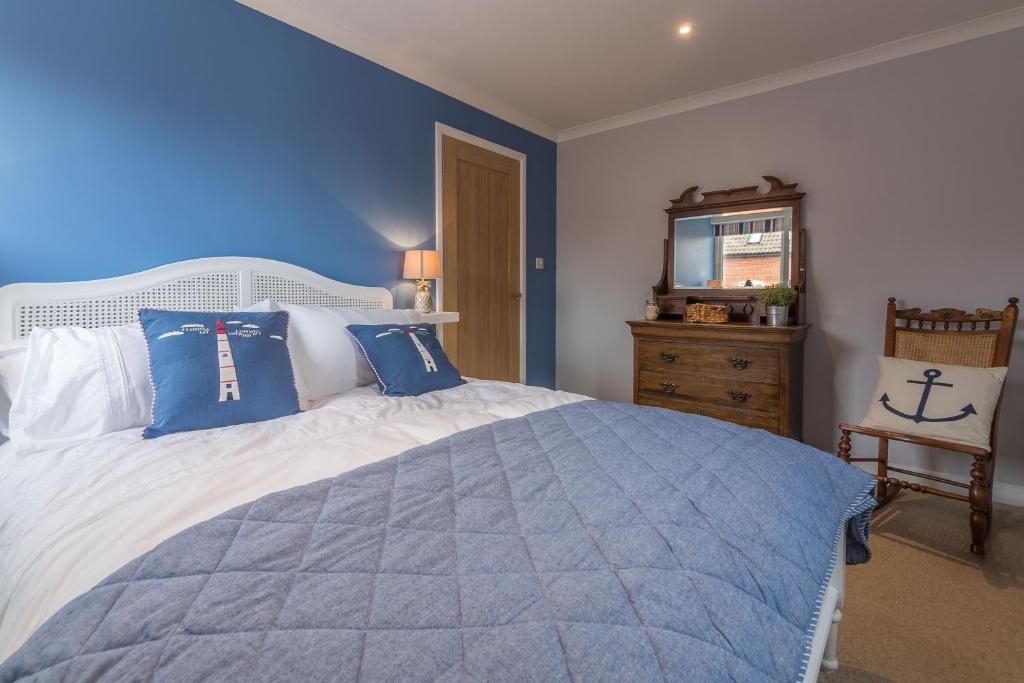 a bedroom with a large bed with blue walls at Kipling House 8 in Wells next the Sea