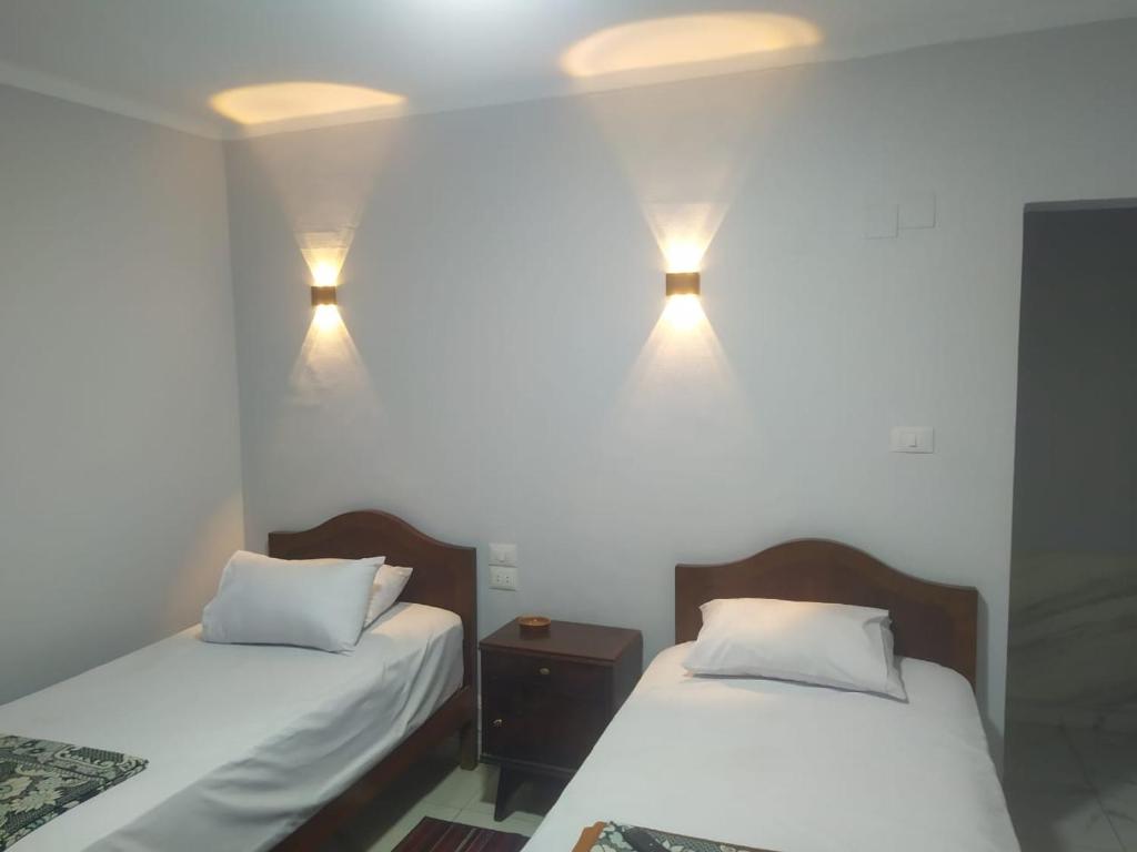 - 2 lits dans une chambre avec des lumières sur le mur dans l'établissement فندق هابى دريمز, au Caire