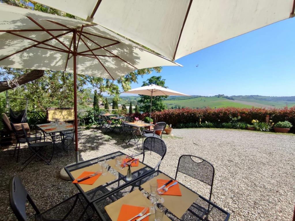 a patio with tables and an umbrella and chairs at Agriturismo Biofattoria l'Upupa in Montalcino