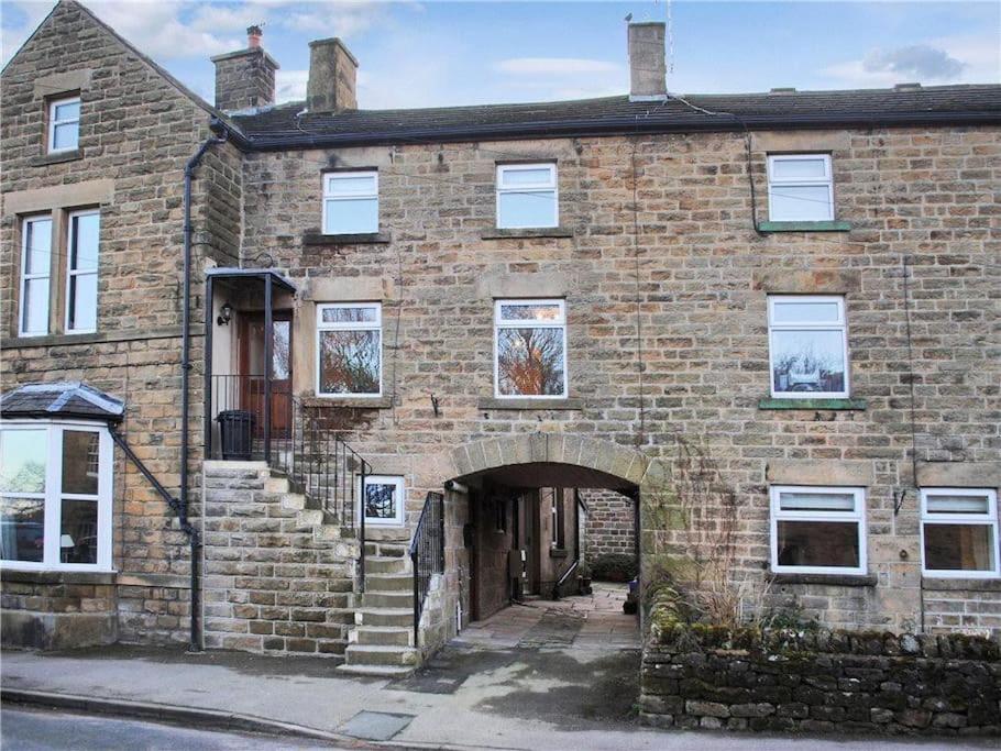 ein altes Backsteingebäude mit einem Torbogeneingang in der Unterkunft Cosy cottage, Pateley Bridge in Pateley Bridge