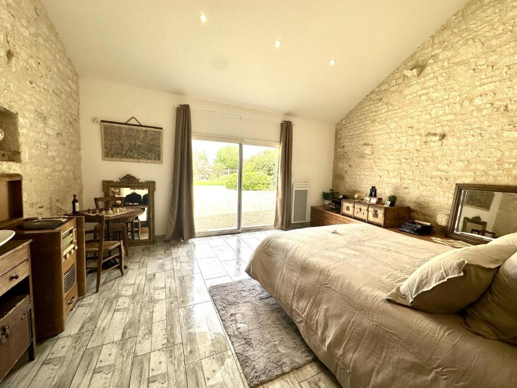 um quarto com uma parede de pedra, uma cama e uma secretária em L'Eden chambre d'hôtes avec jacuzzi et massages em Saint-Aubin-la-Plaine