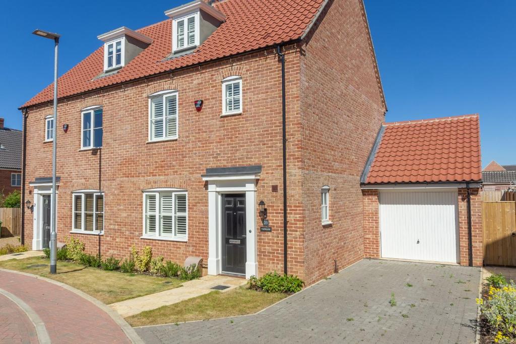 a red brick house with a white garage at Taureans in Wells next the Sea