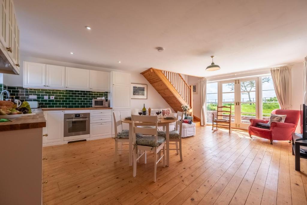 a kitchen and living room with a table and chairs at Gallery Cottage in Wighton