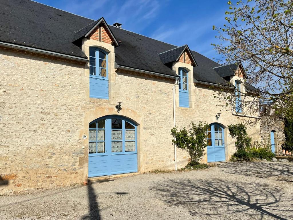 un grand bâtiment en briques avec des portes bleues et un toit dans l'établissement Gîte Poulenc - La Grange de Rocamadour, à Rocamadour