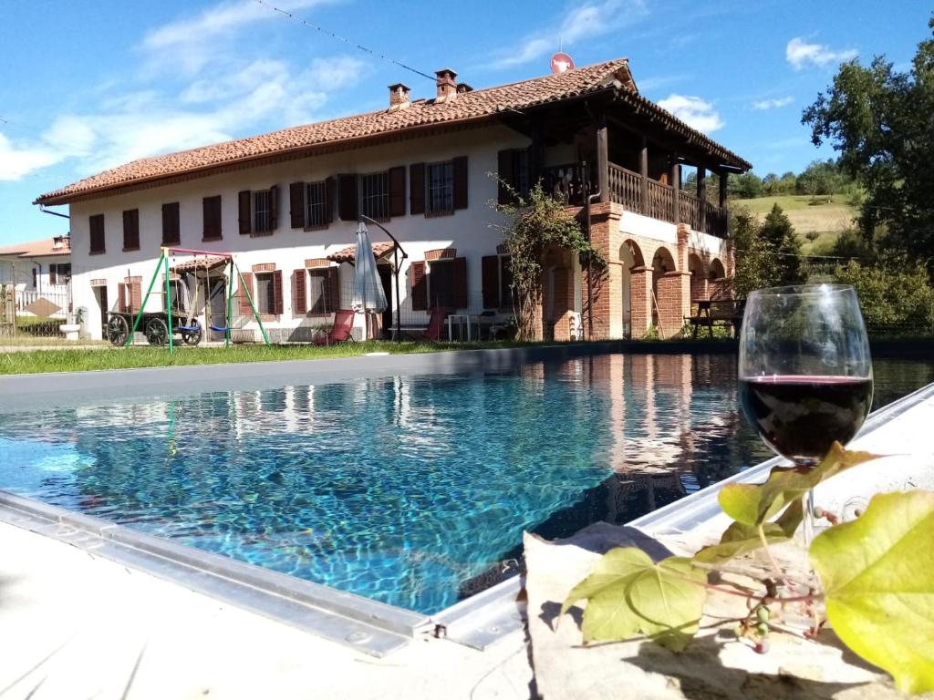 uma casa com um copo de vinho ao lado de uma piscina em Casa delle foglie sussurranti em Asti