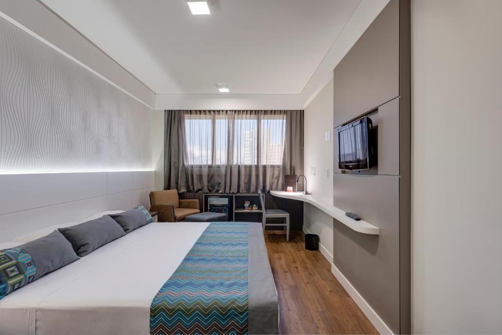 Habitación de hotel con cama y TV en Monreale Plus Midtown Campinas, en Campinas