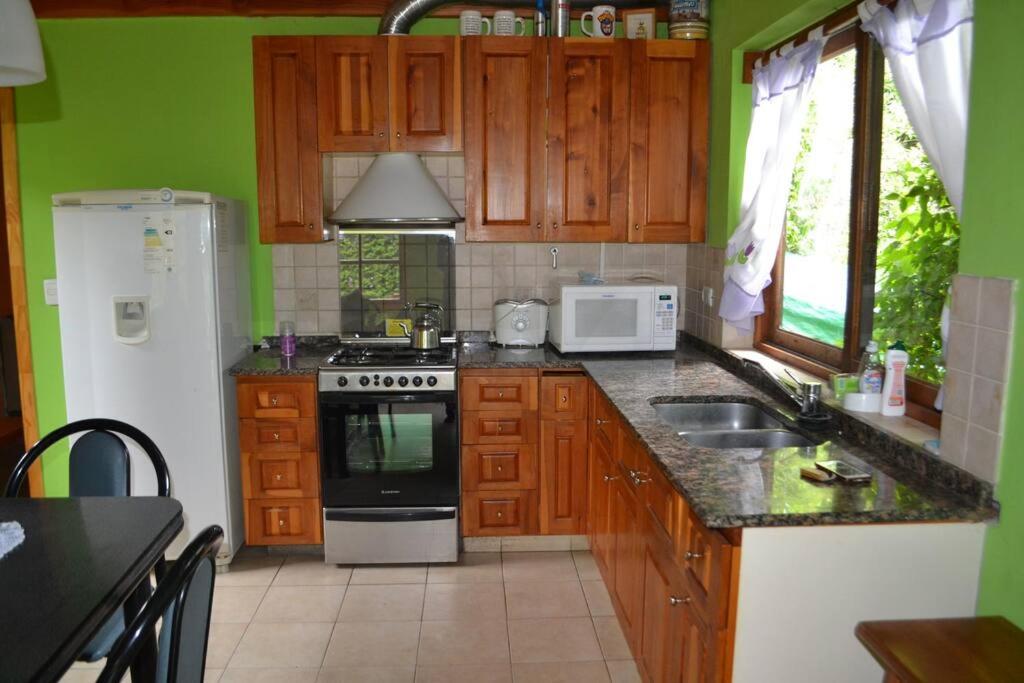 cocina con armarios de madera y nevera blanca en Cómoda cabaña El Castaño en el centro de V.l.A en Villa La Angostura