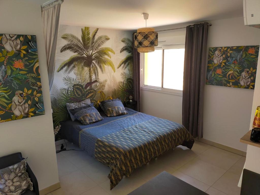 - une chambre avec un lit et une fresque murale de palmiers dans l'établissement Sanguinaires, à Ajaccio