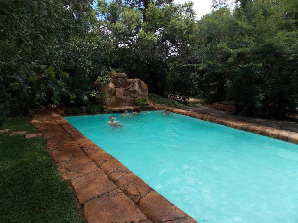 a man in a swimming pool in a yard at Shangrila-innibos Country Lodge in Hartbeespoort