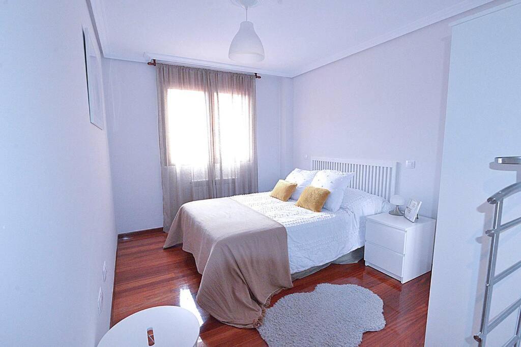 Habitación blanca con cama y ventana en El Apartamento de Adina, en Santiurde de Toranzo